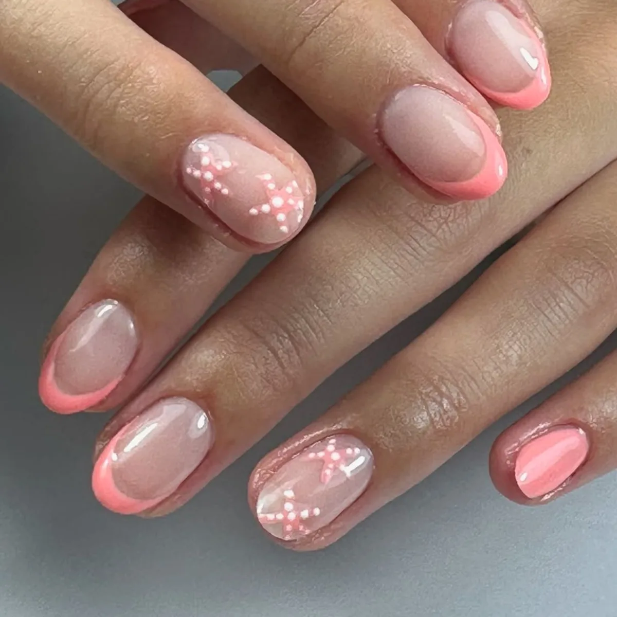 Francesa coral con estrellas de mar blancas en uñas cortas redondeadas