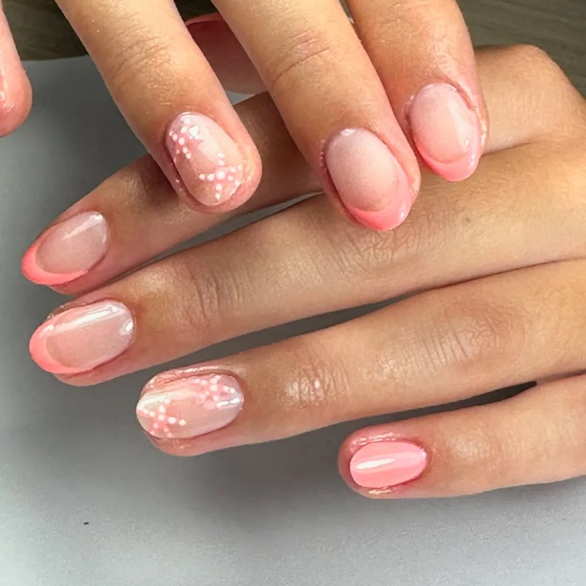 Francesa coral con flores blancas en uñas cortas redondeadas