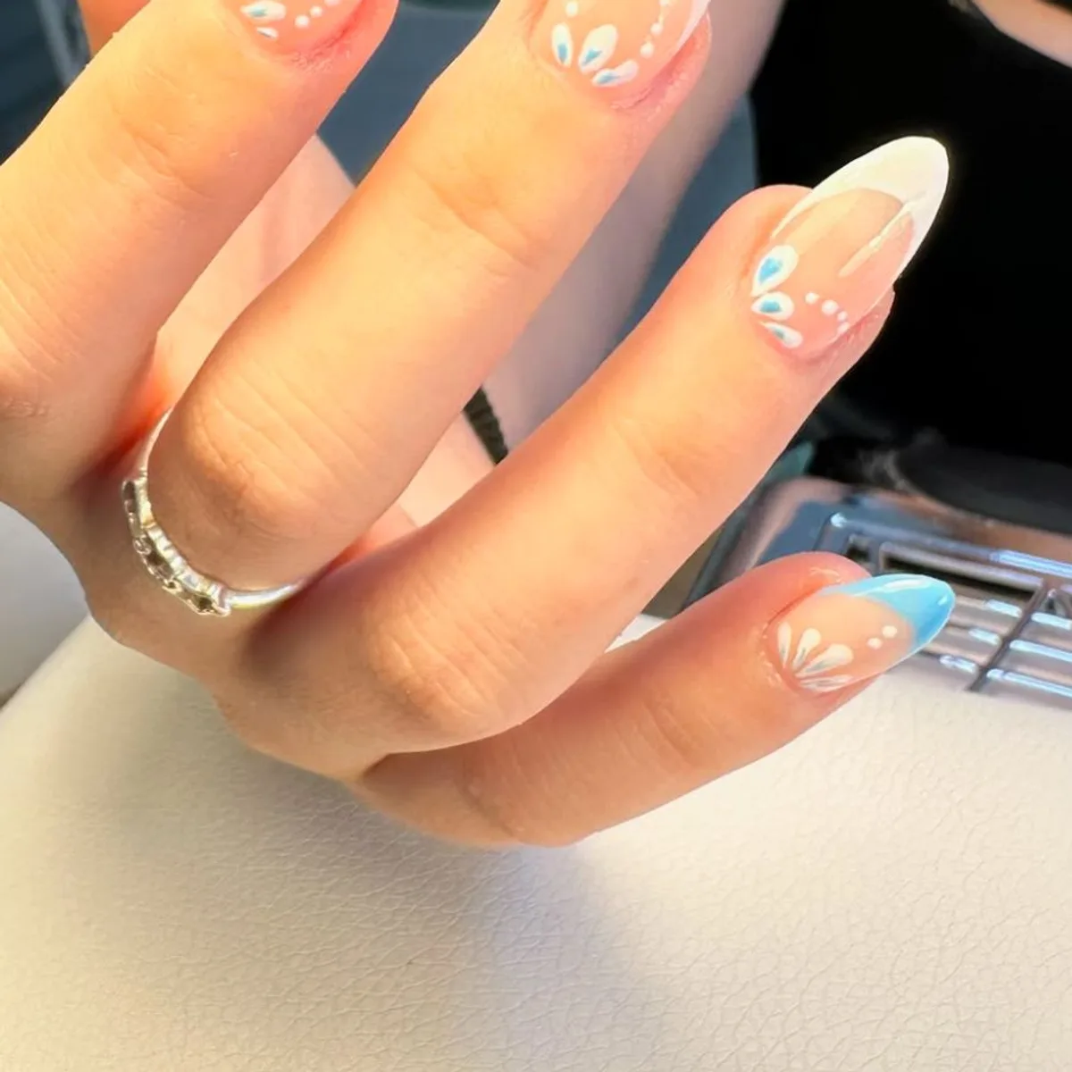 Francesa azul con flores blancas pintadas a mano en uñas almendradas
