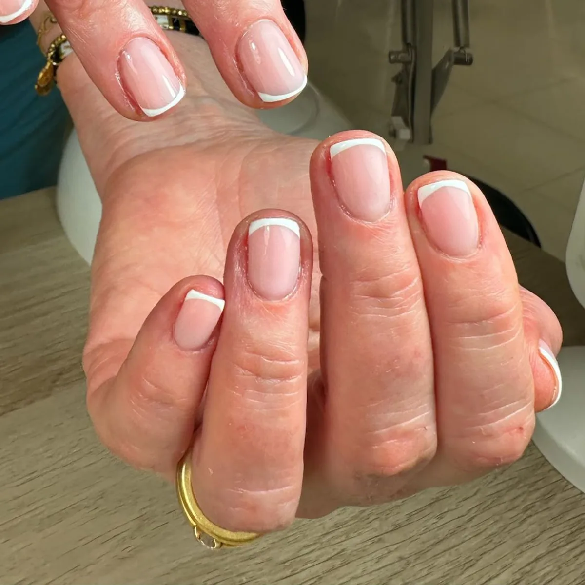 Manicura francesa clásica en blanco sobre uñas naturales cortas